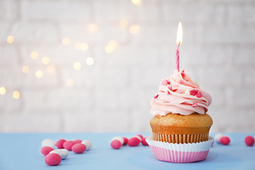 Tasty cupcake with candle on blurred background