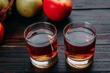 Sweet fresh apple juice and tasty apples on dark wooden table. Organic healthy refreshing drink