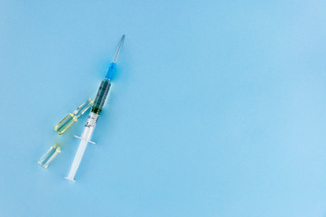 Syringe and small ampoules with medicine on a blue background.