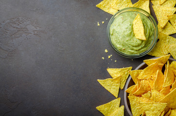 Traditional mexican homemade guacamole sauce in a glass bowl and a bowl with tortilla chips on a...