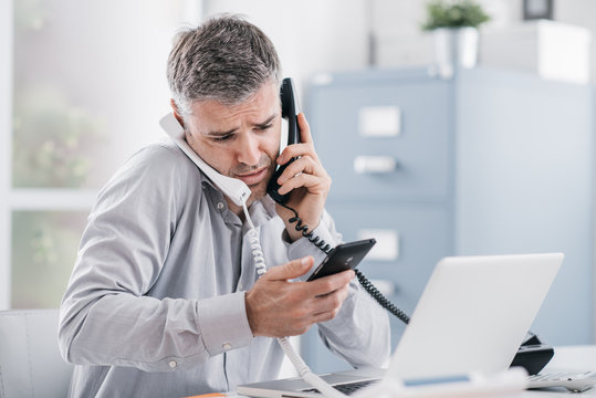 Stressed businessman having multiple calls