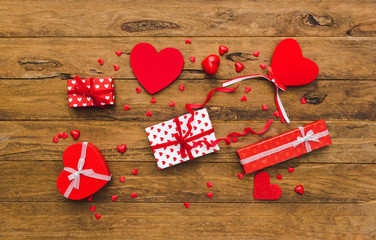 Valentines day background. Gifts tied with ribbon and red hearts on wooden background.