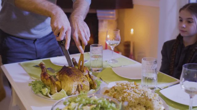 Father cuts a festive fried chicken at the christmas table
