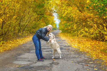 Young girl and dog playing on the road in yellow forest