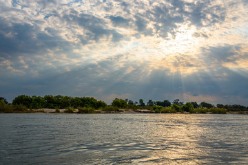 Cloudy skies with dramatic sun rays over the Zambezi river, Zambia, Africa
