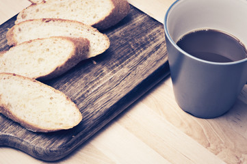 Sliced baguette bread on wooden plate with coffee