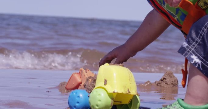 Toddler unloading toy dumptruck on beach - summer fun