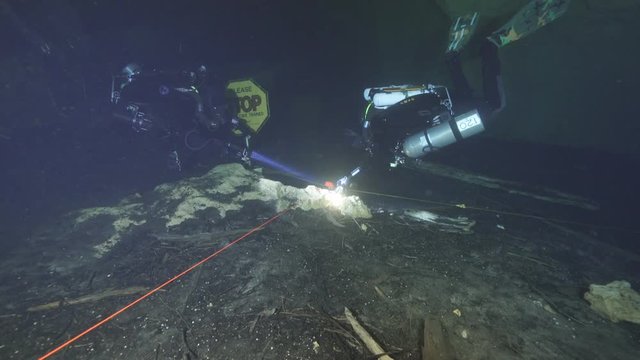 Rebreather divers at underwater cave stop sign