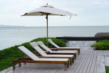 White color recliner beach seating with white parasol facing the sea front in Thailand