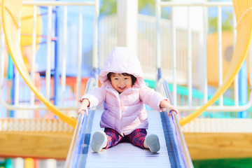 公園の滑り台で遊ぶかわいい子供