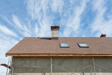 New roof with skylight, asphalt roofing (shingles) and chimney. Roof with mansard windows .
