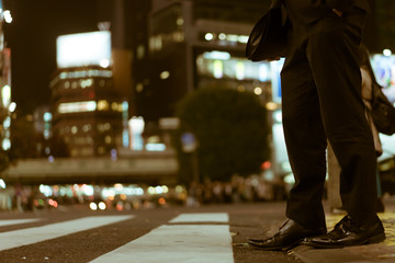 Businessman legs waiting to cross the famous Shibuya Crossing, Tokyo, Japan