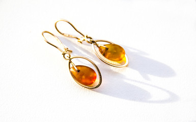 Fototapeta premium Gold earrings with amber on the light background