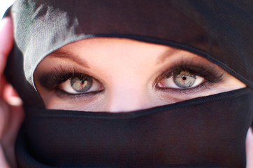 Woman face portrait with deep eyes and eyelashes beauty make up, wearing black scarf niqab hijab around face and neck, photo session in arabic mysterious authentic mystic fairy style, beauty fashion