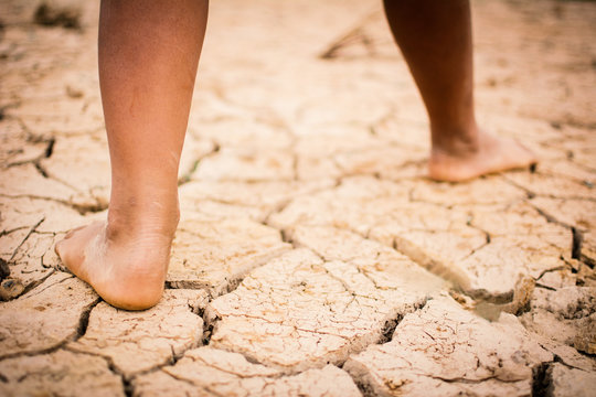 Feet of boy on cracked dry ground .concept hope and drought