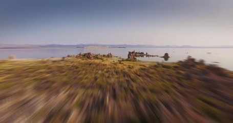Fast low altitude aerial flight over desert landscape toward beautiful Mono Lake