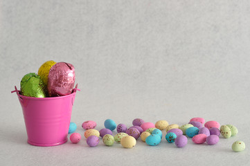 A bucket filled with easter eggs and some small ones laying next to it isolated against a white background