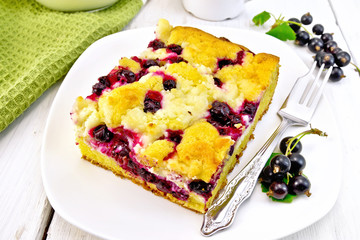 Pie with black currant in plate with fork on light board