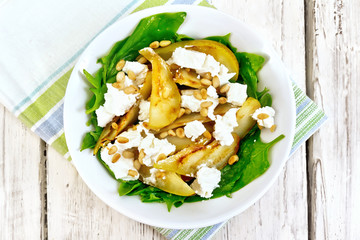 Salad from pear and spinach in dish on light board top