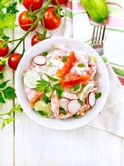 Salad from fresh vegetables in plate on light board top