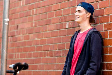 Fototapeta na wymiar Teenage boy with skateboard standing next to the wall