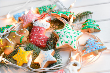 Christmas cookies with festive decoration and christmas lights on white wooden background. New Year and Christmas concept.