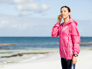 Sporty woman with earphones on the sea coast