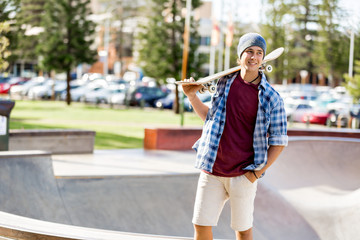 Teenage boy with skateboard standing outdoors © Sergey Nivens