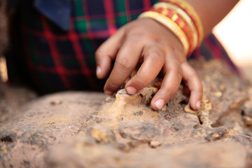 Obraz na płótnie Canvas Hand of little Indian girl with bracelets on a wrist rests on a stone