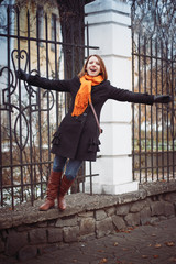 Portrait of a young woman in a black coat and red scarf in the city