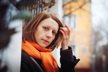 Portrait of a young woman in a black coat and red scarf in the city
