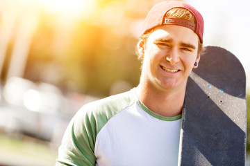 Teenage boy with skateboard standing outdoors