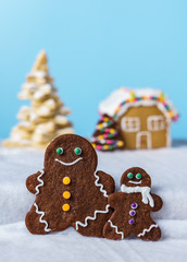 home made delicious traditional gingerbread village and gingerbread man family blue background.