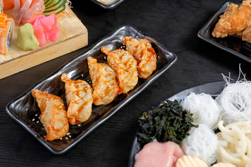 Gyoza (Japanese-Style Pan Fried Pork and Cabbage Dumplings) with spicy sauce on black dise