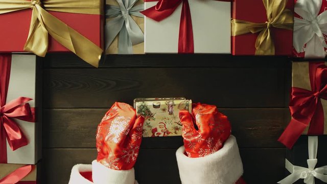 Santa spins with fidget spinner and puts it in gift box on Christmas table, top down shot