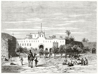 Ancient white colonial edifice in Sudan on a rocky large square with trees and few people. Place de la Mudirie in Khartoum Sudan. By Girardet after Lejean published on Le Tour du Monde Paris 1862