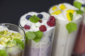 Top view on milk cocktails with blueberries, raspberries and mint leaves against black background
