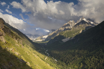 Obraz premium Summer views of the snowy mountains of the Caucasus. Formation and movement of clouds over mountains peaks.