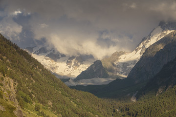 Summer views of the snowy mountains of the Caucasus. Formation and movement of clouds over mountains peaks.