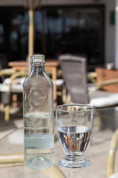 Cold fresh water in glass bottle with glass on a cafe table, vertical image