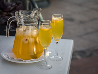 Yellow champagne sangria served in a mug with two glasses