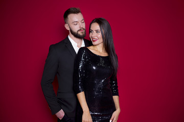 Male and female embrace each other. Beautiful couple in black luxury dress on a red background. Valentine's Day. Women's Day. March 8