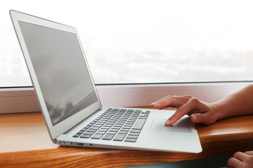 Close up of hands typing on a laptop in a coffee shop