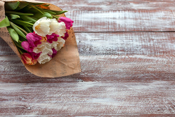 the bouquet of tulips is wrapped in a paper isolated on a wood background
