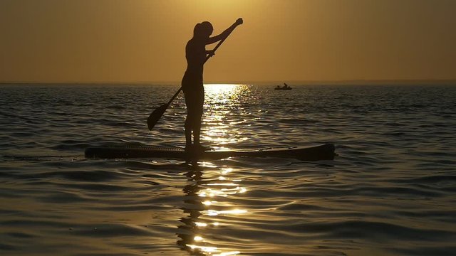Paddleboard floats solar path at sunset