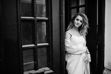 Obraz premium Stylish curly blonde model girl wear on white posing against old wooden door.