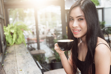 Portrait of Asian woman drinking coffee in coffee shop , outdoor in sunlight light, enjoying her morning coffee.