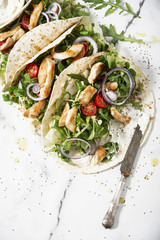 Unwrapped tortilla with fresh salad and roasted chicken and a bowl of sauce. Top view shot. Gourmet conception.