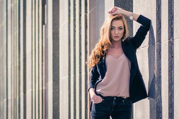 Outdoors fashion portrait of trendy pretty girl posing on the wall background.