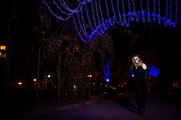 Halloween skull make up girl wear in black at night street of city.
